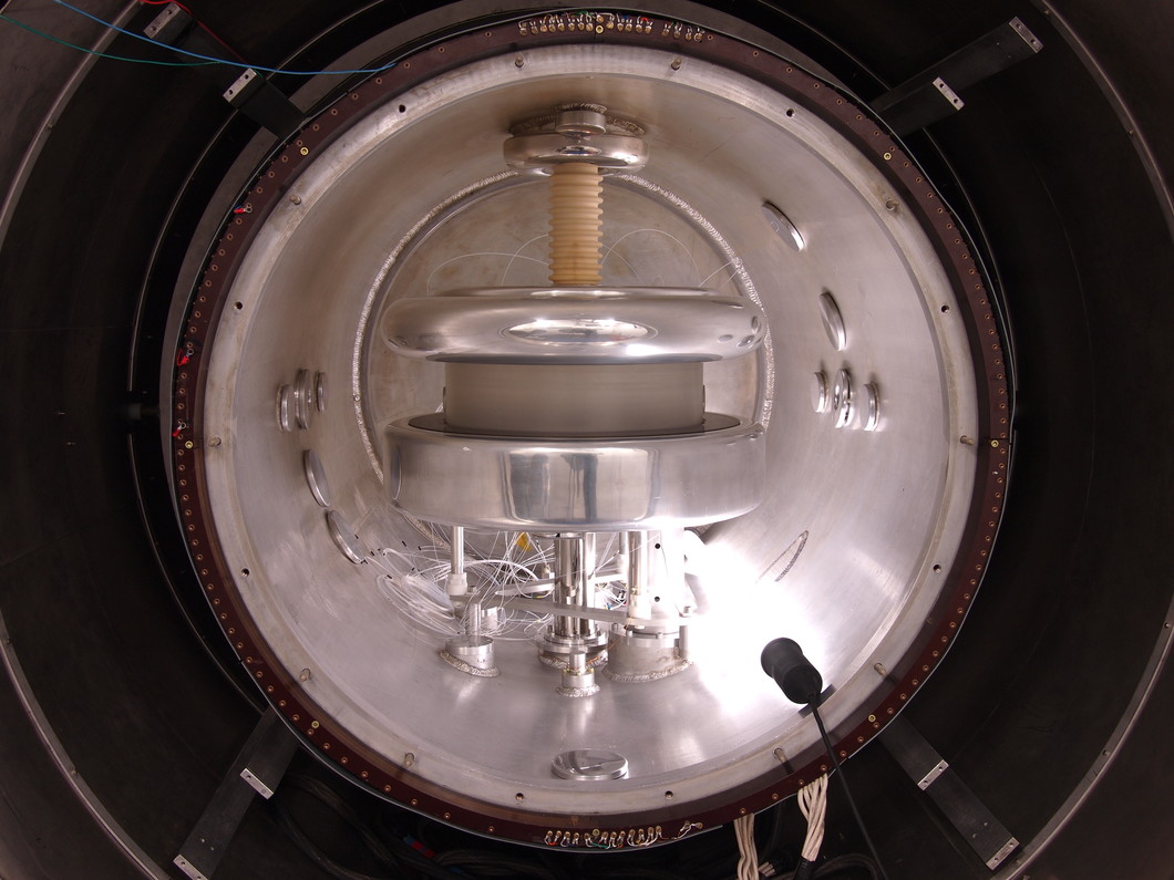 Vue dans un spectromètre qui prend la mesure du moment dipolaire du neutron. Le diamètre du réservoir en aluminium s'élève à un mètre. Il est entouré, dans la partie sombre, d'un bouclier magnétique qui diminue le champ magnétique de la terre du facteur 10'000. (Photo : PSI/Zema Chowdhuri)