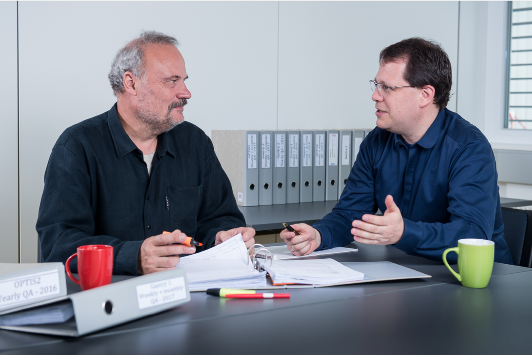 Gerhard Aigner (right), who is responsible for safety and quality management at the Centre for Proton Therapy, keeps track of the 350 plus safety tests carried out each year. Here he discusses the results of a recent test with physicist Martin Grossmann. (Photo: Paul Scherrer Institute/Mahir Dzambegovic)