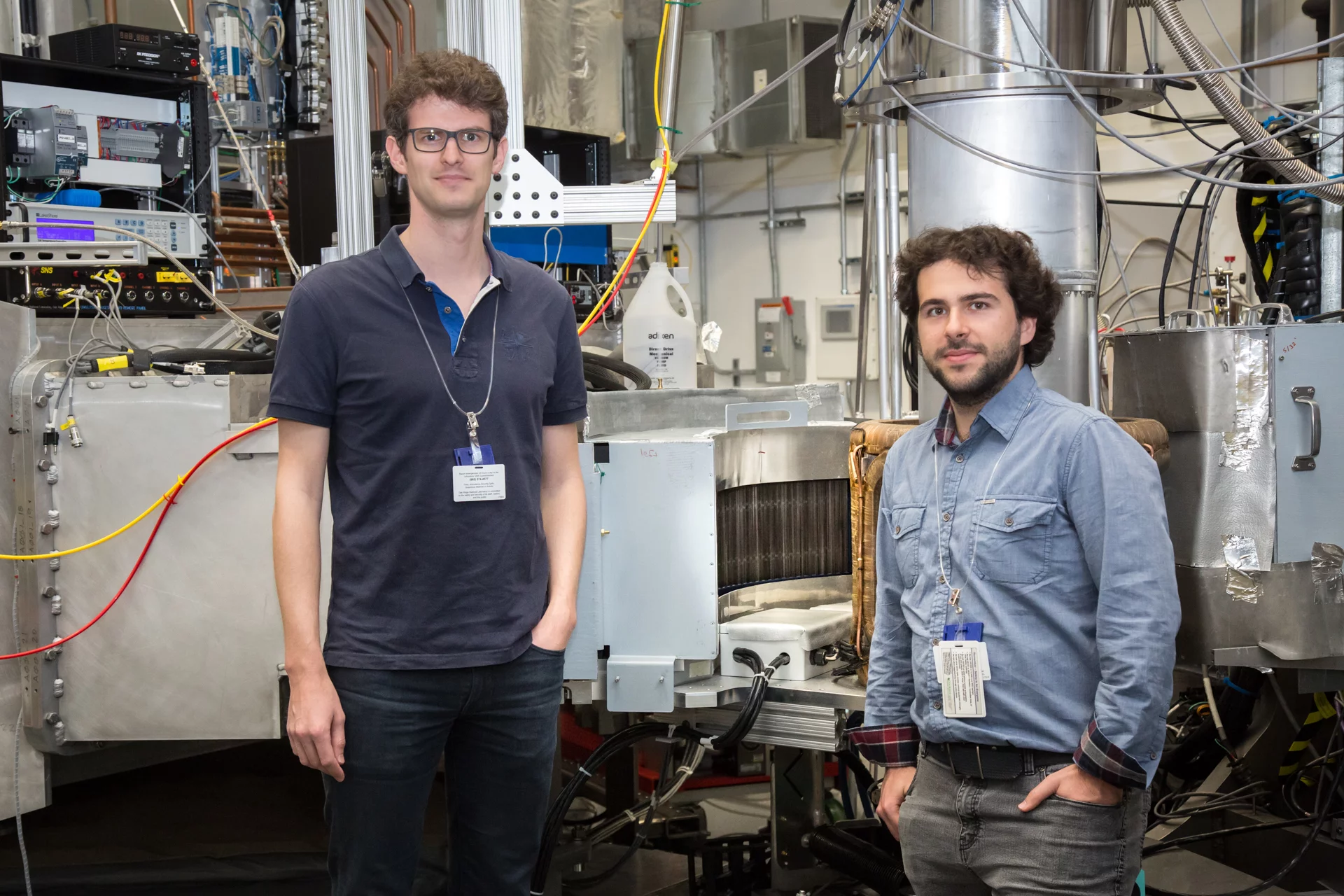 NUM researchers Romain Sibille (left) and Nicolas Gauthier at Oak Ridge National Laboratory (US), in front of the HYSPEC spectrometer, and its polarization analyser designed and built at PSI. The spectrometer has been instrumental in their study of the quantum spin ice Pr2Hf2O7.(Image credit: ORNL/Genevieve Martin)